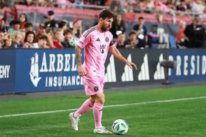 Soccer player in pink uniform controls the ball near the sideline during a match.