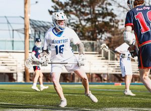 Wide angle view of lacrosse players positioning during a match on an artificial turf field.