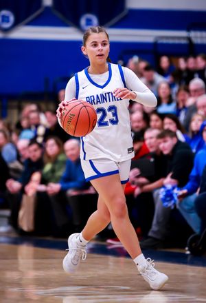 Basketball player dribbles low across court in blue and white uniform during game.