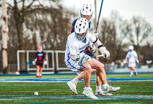 Low angle shot of lacrosse players' cleats and sticks during gameplay.