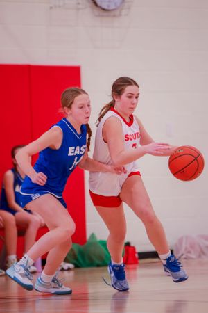 Two basketball players from opposing teams compete for possession of the ball during an intense game.