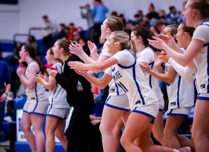 Basketball team bench players celebrate and cheer during exciting game moment.