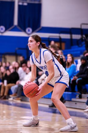 Basketball player in blue uniform demonstrates defensive stance during game.
