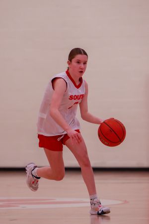 Basketball player in white uniform dribbles the ball during a game.