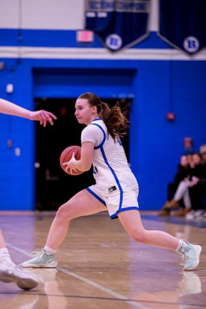 Basketball player lunges forward while dribbling during intense game action.