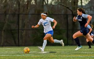 Soccer players diving and sliding on a grass field during an intense match.