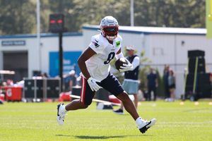 Football player sprints across the practice field in training gear.
