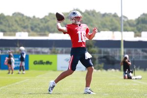 Football player throws a pass during practice on outdoor training field.