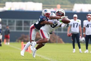 Football players compete for the ball during an intense defensive play at practice.