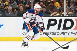Hockey players from the Oilers and Bruins face off during a competitive NHL match.
