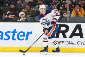 NHL players from the Oilers and Bruins battle during a competitive match.