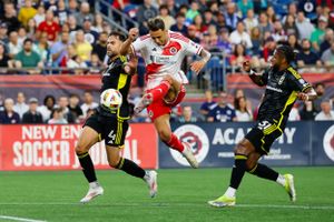 Soccer players from opposing teams battling for ball possession during intense match.