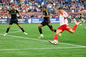 Soccer players competing for ball control during professional match on grass field.