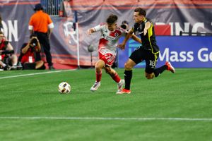 Soccer action shot showing players fighting for ball possession during competitive match.