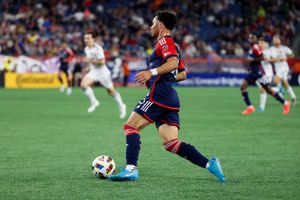 Soccer match action with players from opposing teams pursuing the ball.
