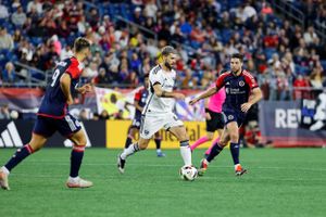 Soccer players chase after the ball during an intense match on a professional field.