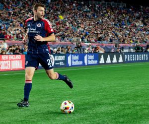 Players chase the ball during a professional soccer match with stadium signage visible.