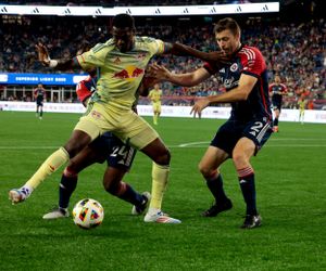Soccer players battle for possession of the ball during an intense match between teams in red and yellow uniforms.