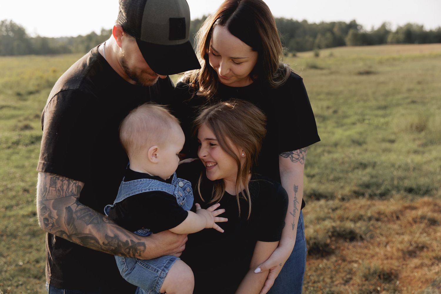 Family enjoying tender moments together in a golden field at sunset.