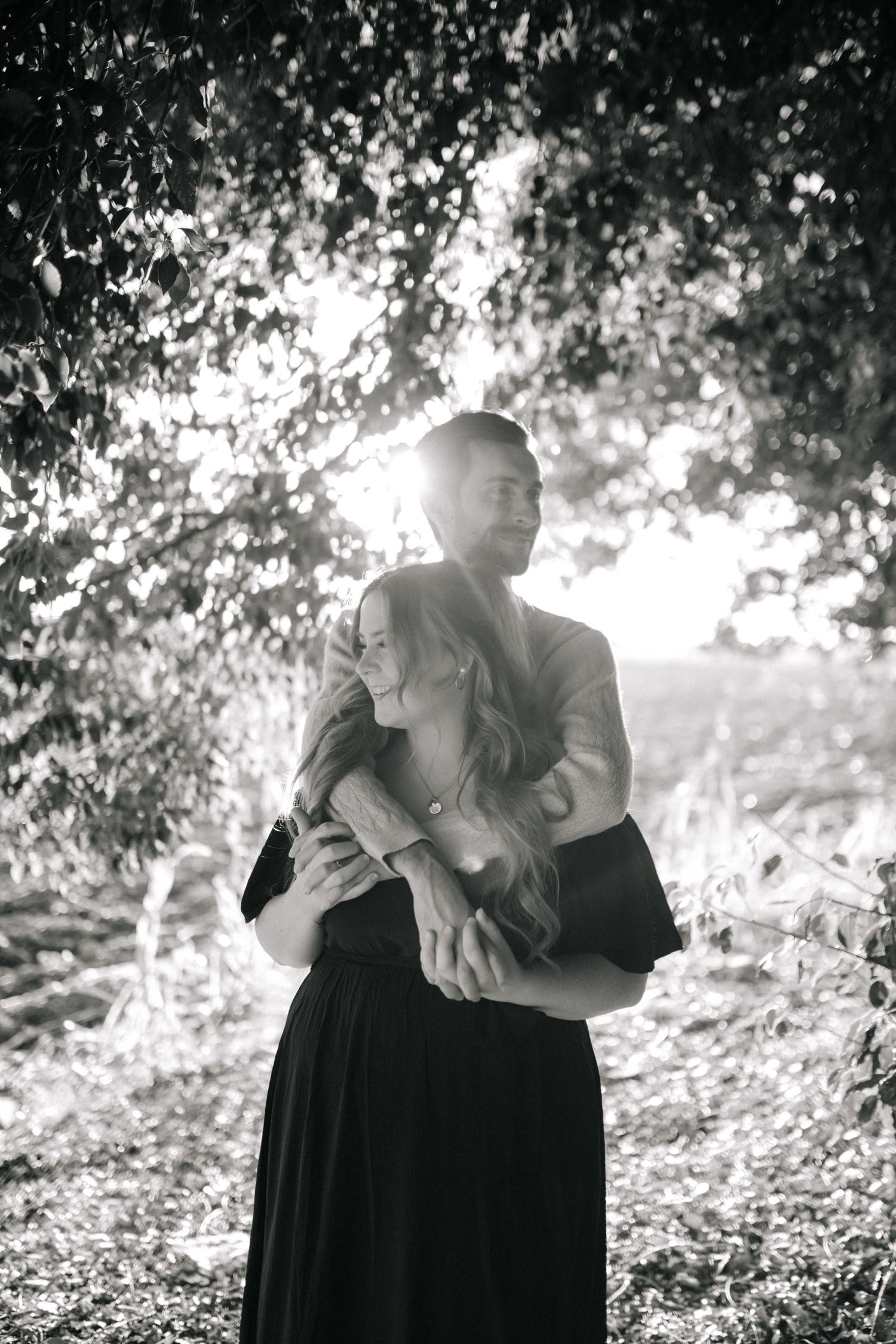 A romantic black and white photo sequence showing an intimate embrace between two people in a sunlit outdoor setting.