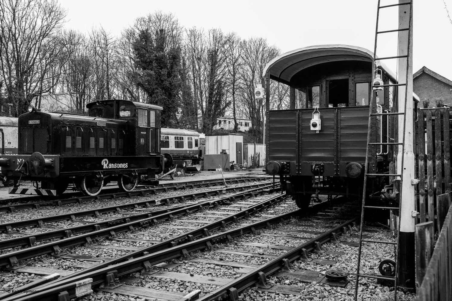 A series of vintage black and white photographs showing historic railway cars and tracks at a train station.
