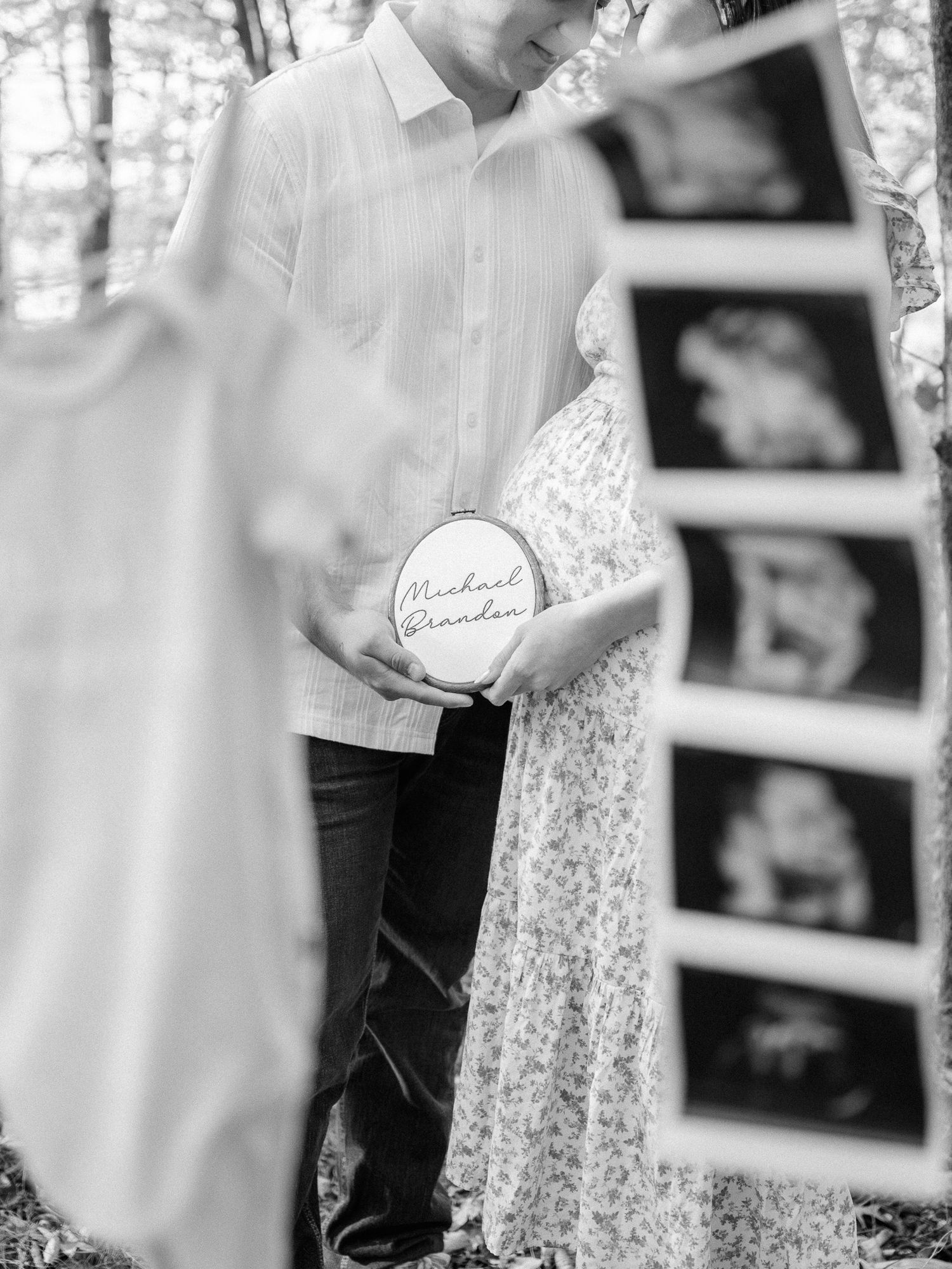 Black and white photo of ultrasound images hanging on a clothesline with baby items.
