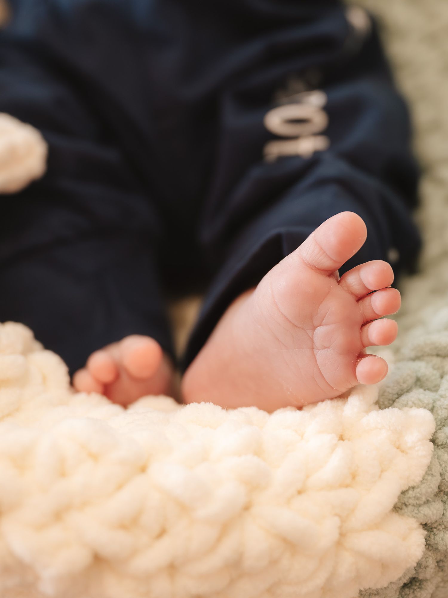 Tiny baby feet resting on a soft cream-colored blanket.