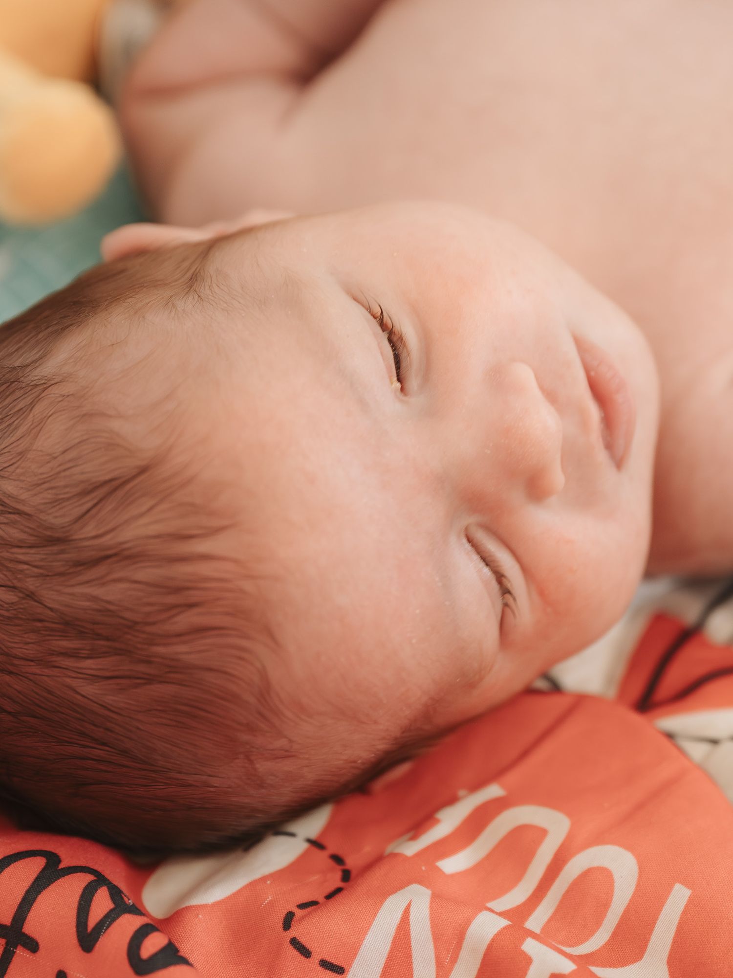Close-up shots of a sleeping baby resting on a red surface.