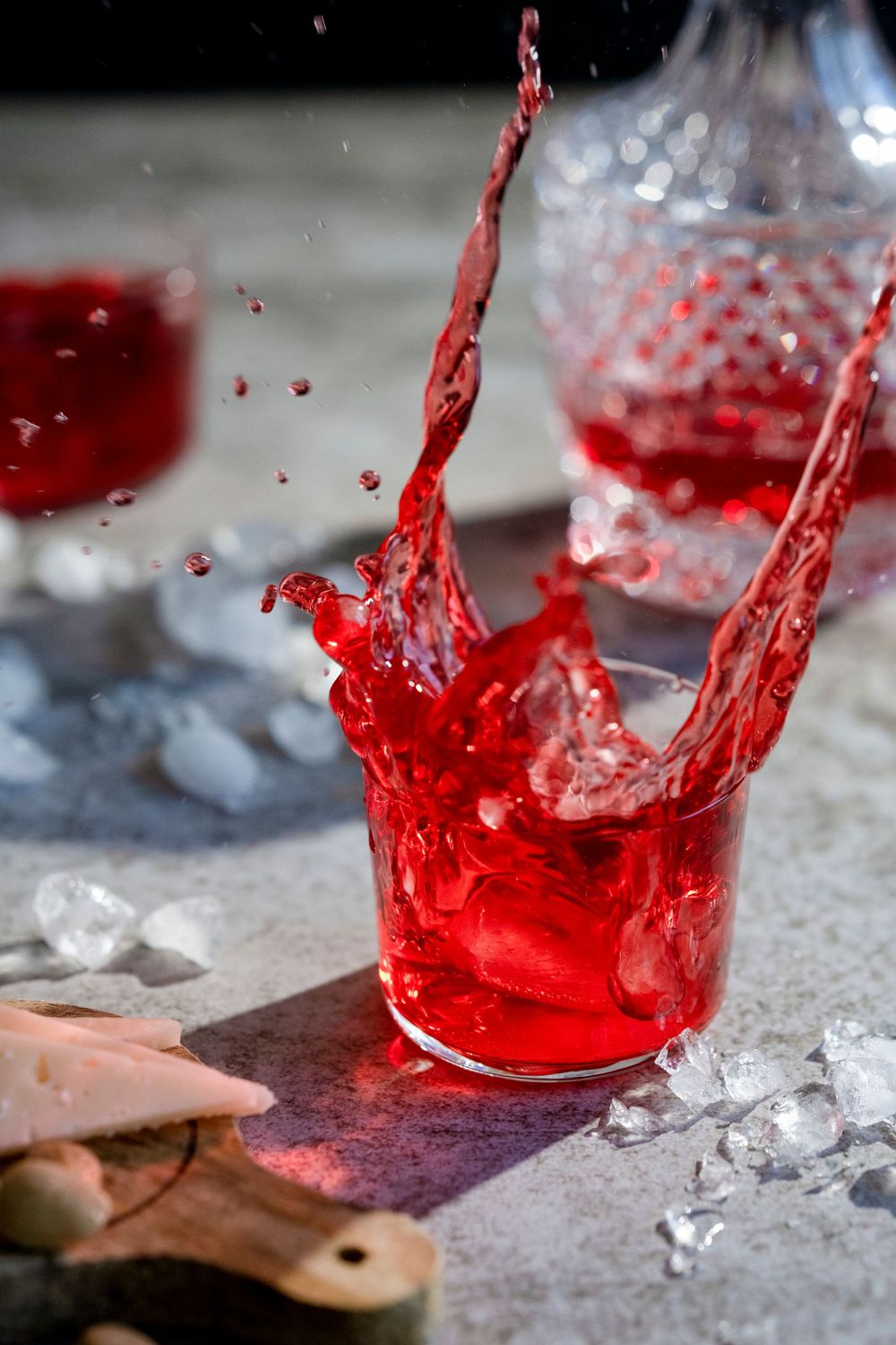 Dynamic splash of red liquid against ice cubes in high-speed photography.