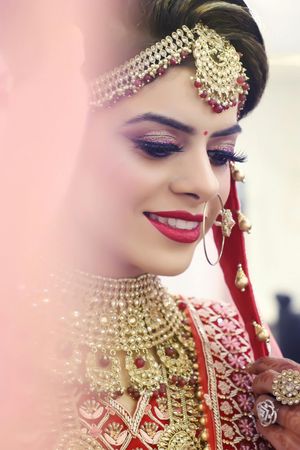 Close-up of traditional Indian bridal jewelry and makeup featuring ornate gold necklace and red lipstick.