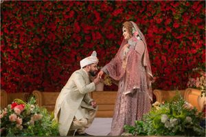 A couple shares a romantic moment in front of a stunning wall of red roses during a proposal.