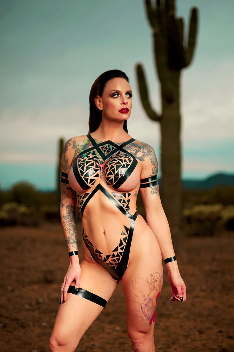Female model in black body tape posing in the desert