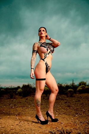 Female model in black body tape posing in the desert