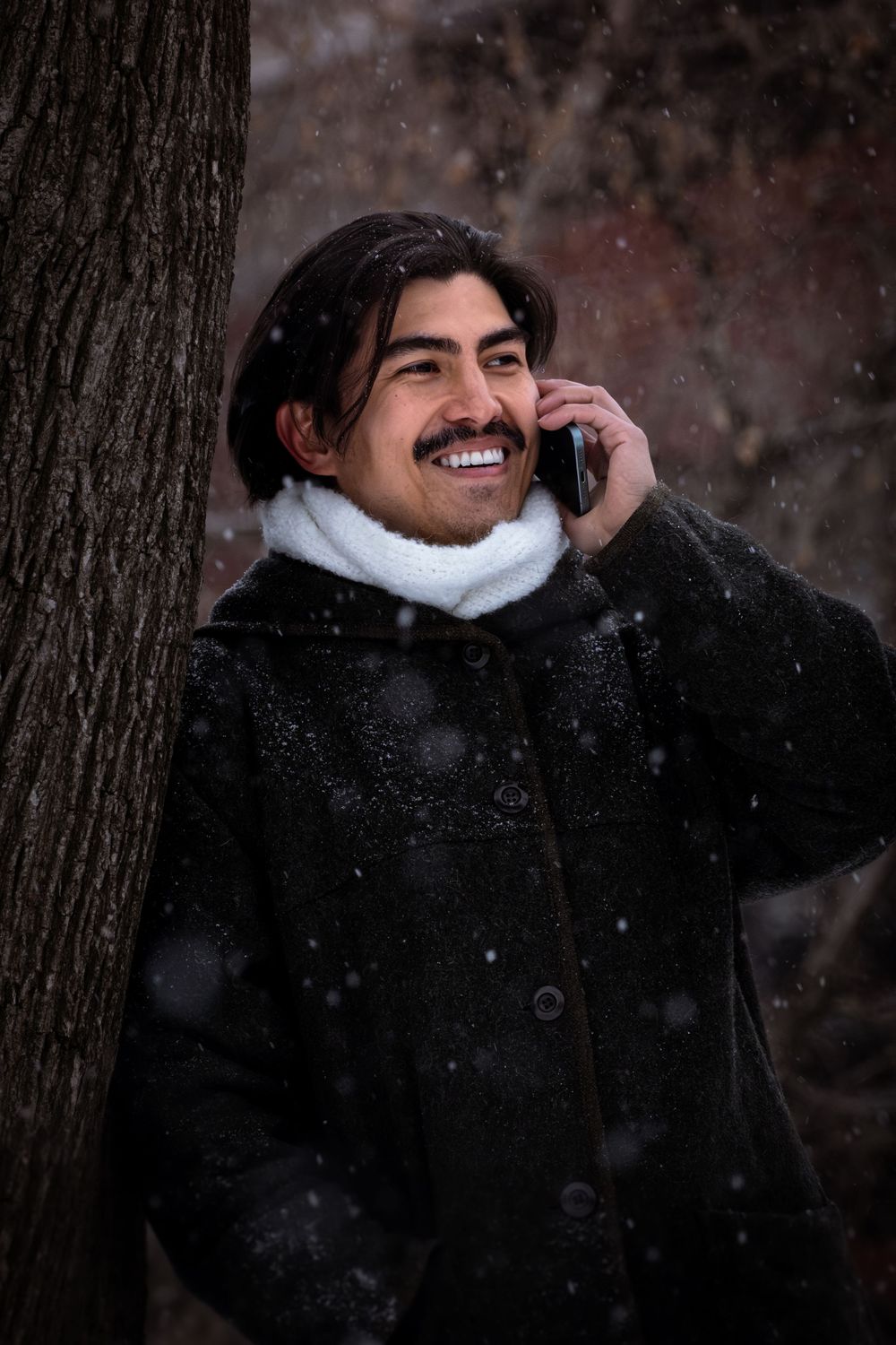 A sequence of expressive winter portraits showing joyful emotions while snow falls in a wooded setting.