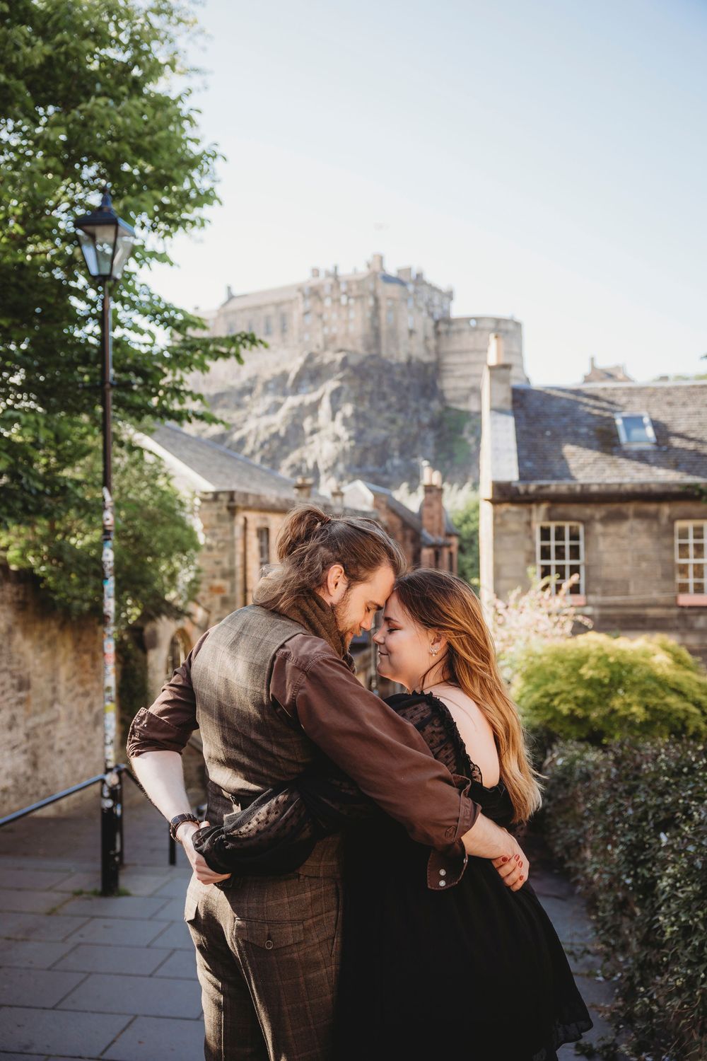 A romantic couple embraces with Edinburgh Castle as a stunning backdrop in Scotland.