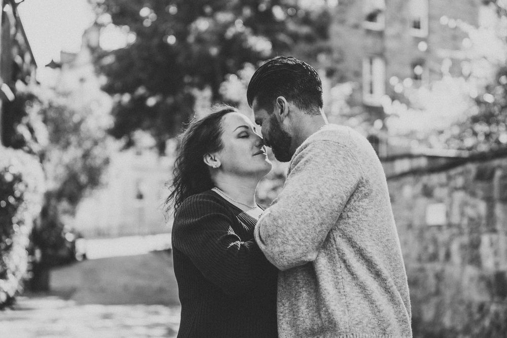 A romantic couple embraces outdoors in a black and white photo collage showing multiple tender moments together.
