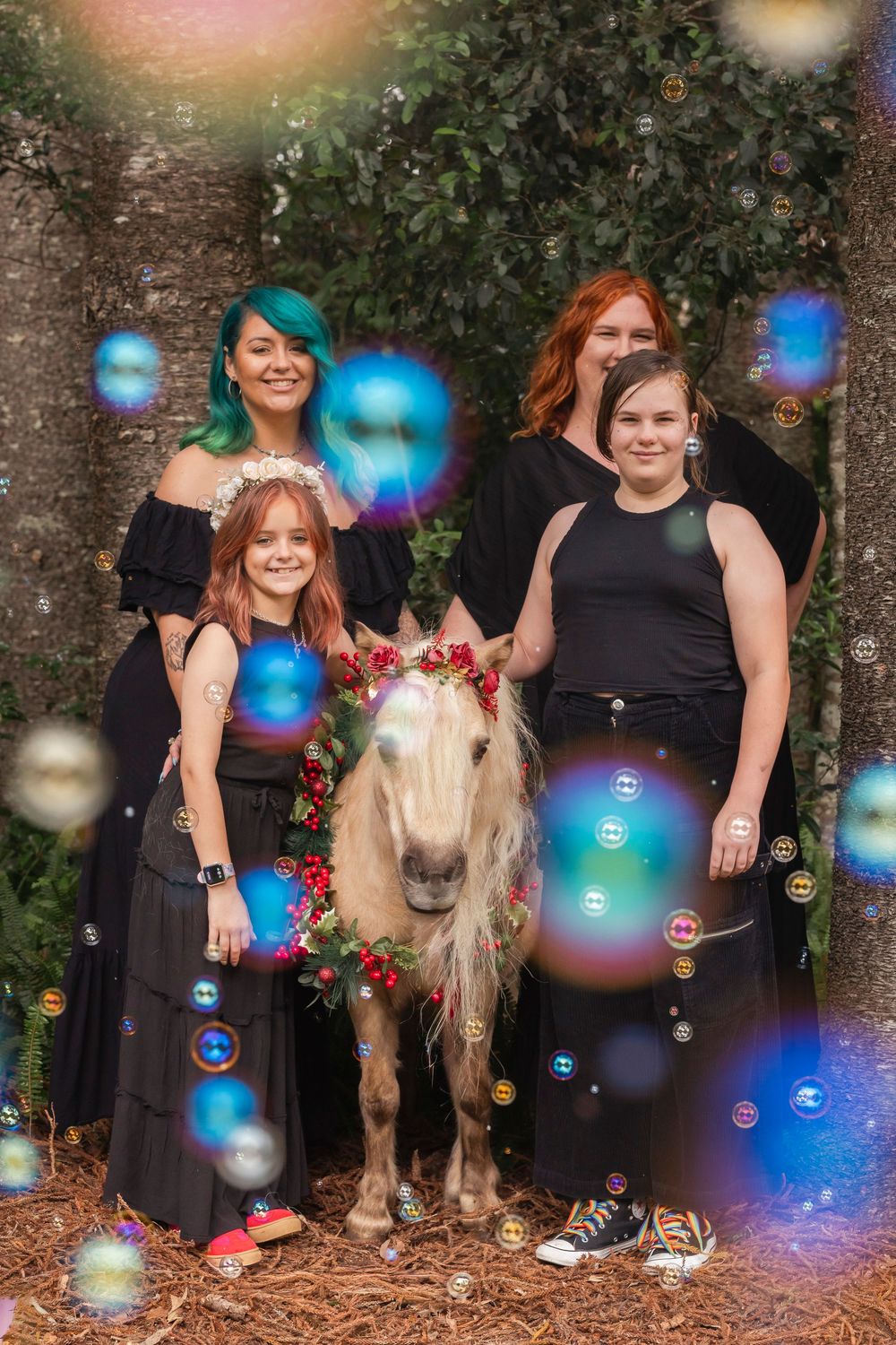 Dreamy outdoor photoshoot with floating bubbles and a white pony against tree backdrop.