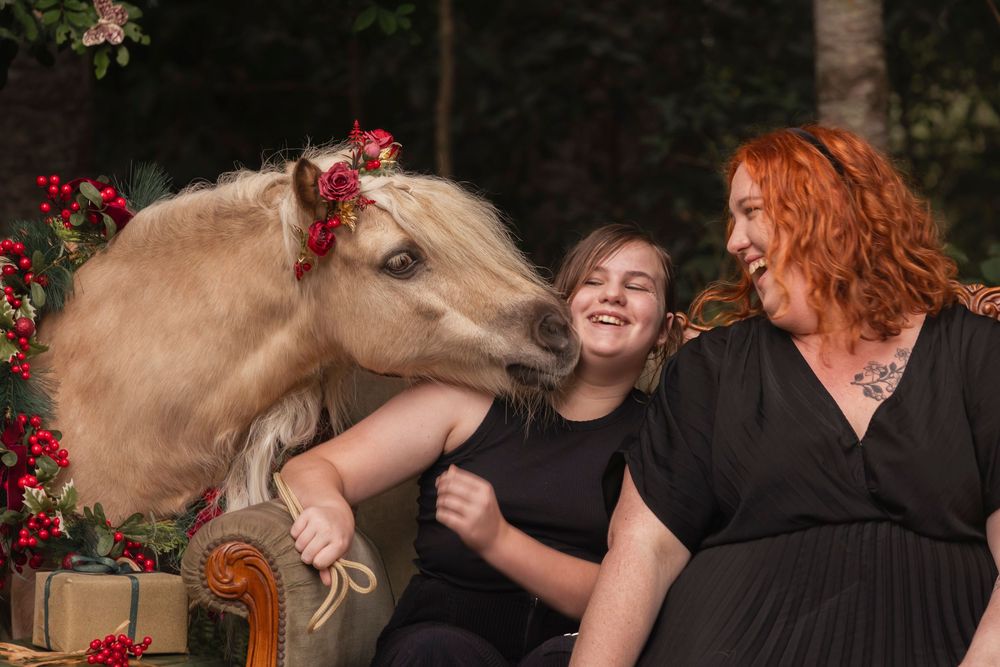 Casual outdoor gathering with a decorated white pony and red floral accents.