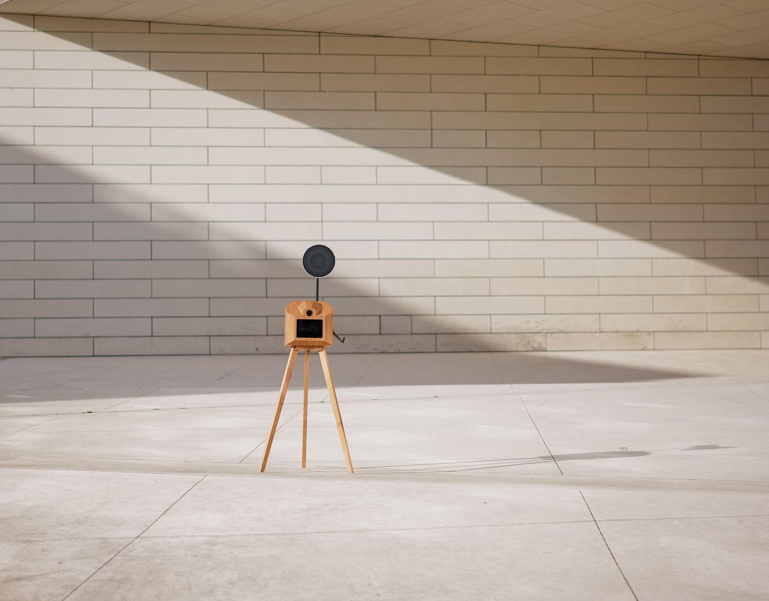 A minimalist art gallery wall with white brick texture and dramatic angular shadows cast across the floor and surface.