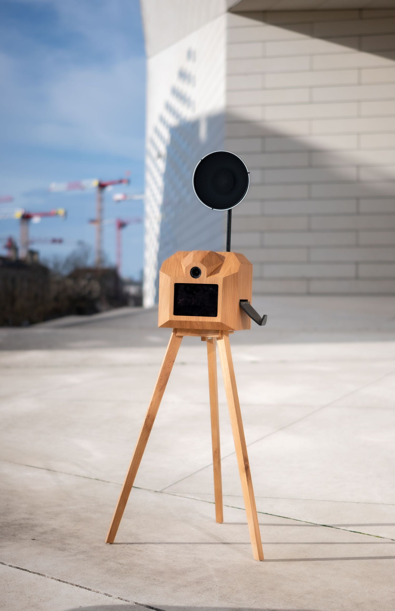 Wooden stool with black circular seat shown from multiple angles on a light concrete floor.
