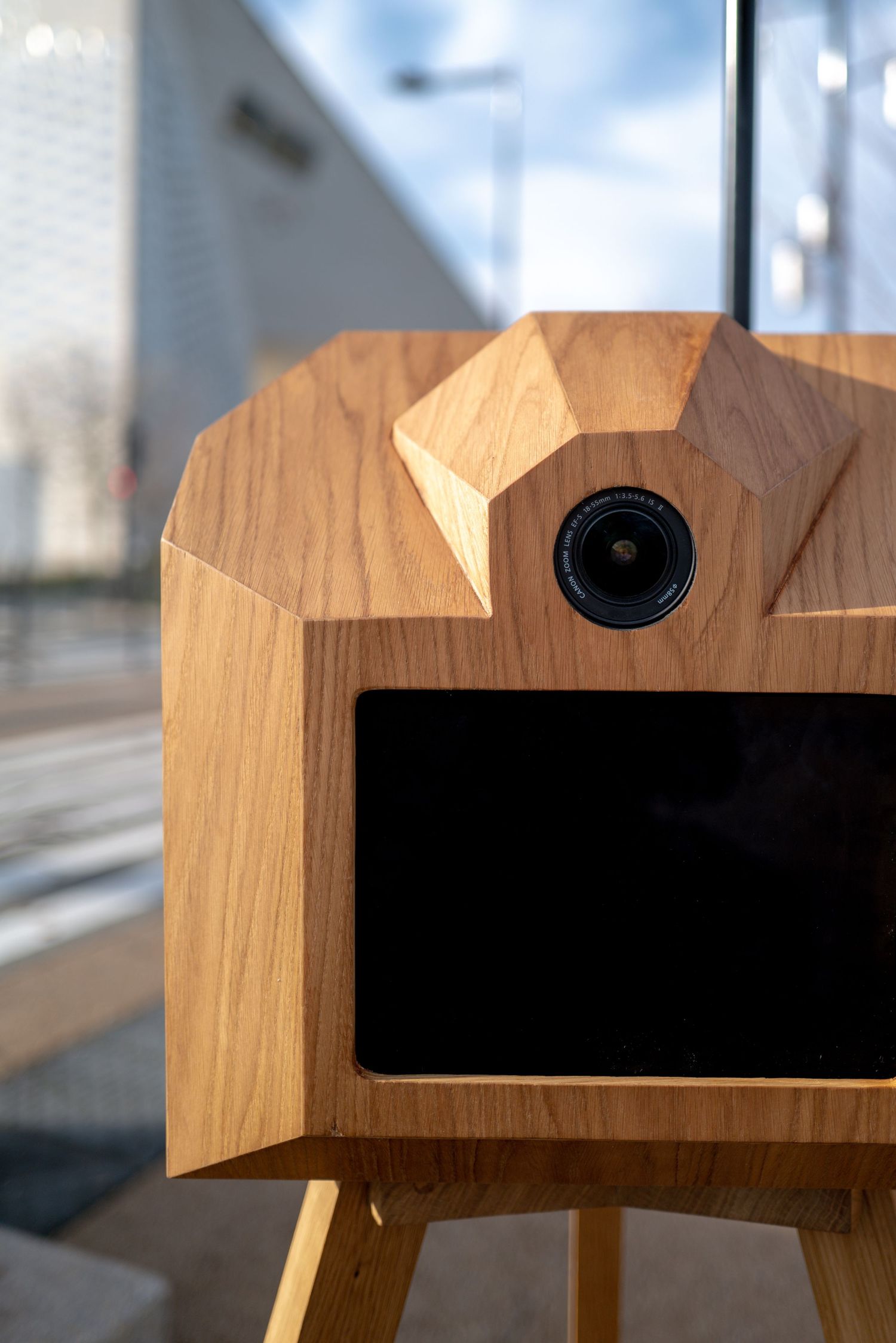 Close-up series showing a wooden camera design with geometric angular cuts and a lens opening in natural oak material.