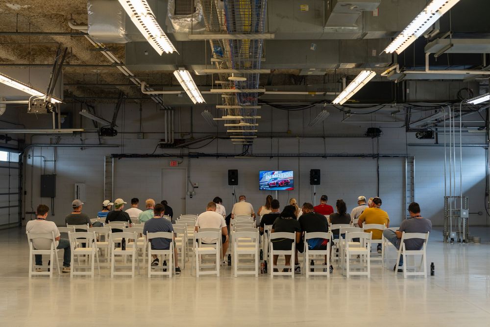 Wide view of an empty conference room with white chairs and industrial ceiling.