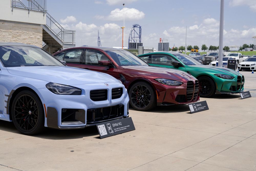 Line of luxury sports cars parked under blue sky with white clouds.