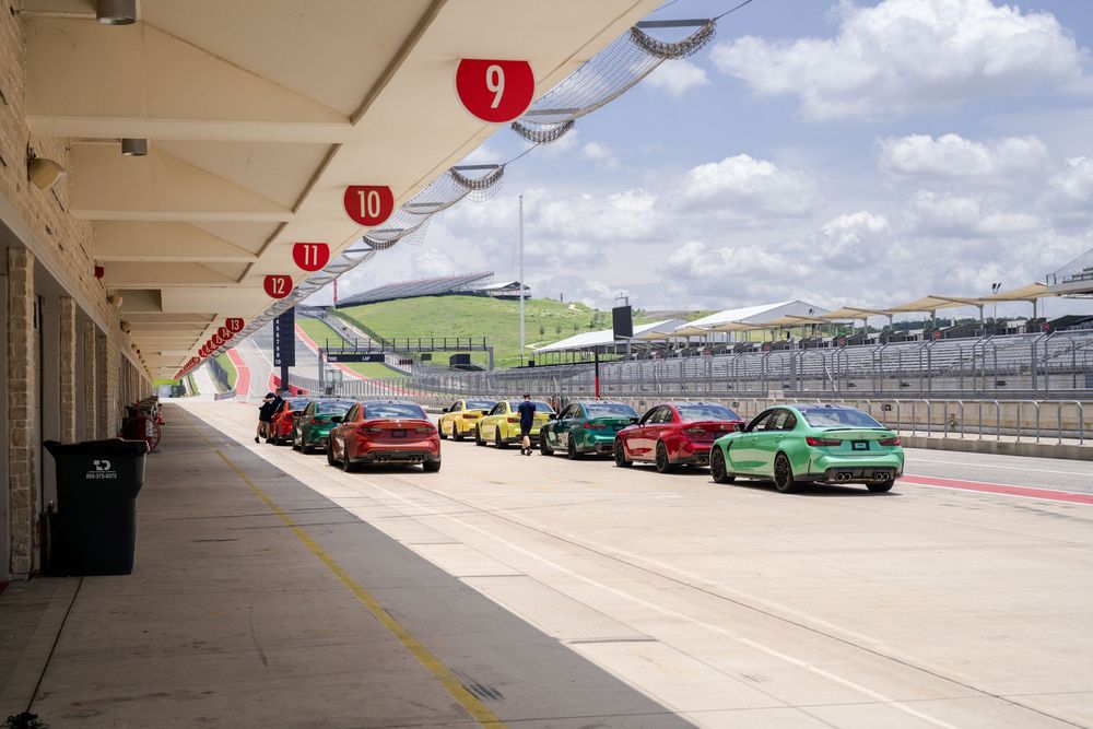 Race track pit lane with covered walkway and parked performance vehicles.