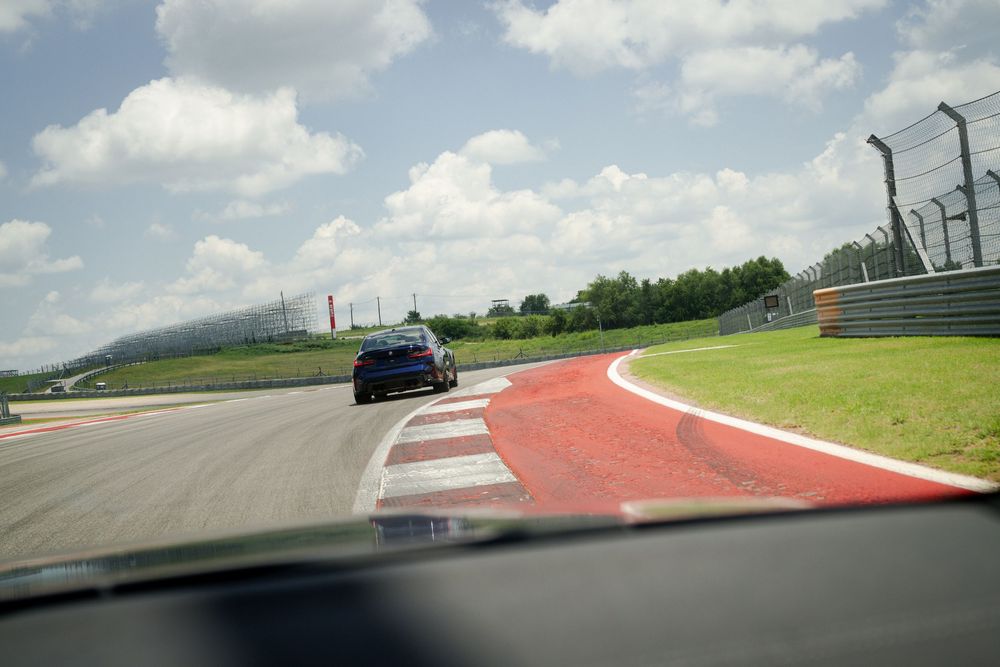 Racing circuit track with red and white curbing under partly cloudy sky.