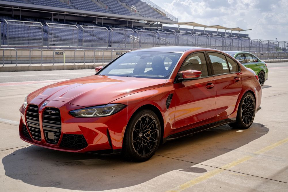 Red BMW M4 performance vehicles displayed on a racetrack.