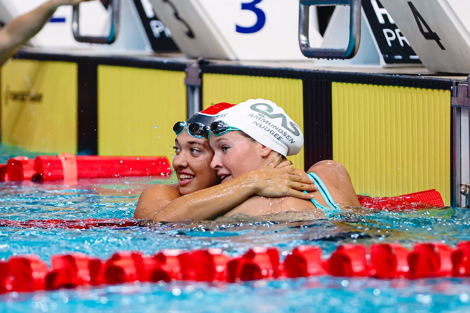 A swimmer celebrates in the pool after completing a race, splashing water in excitement.