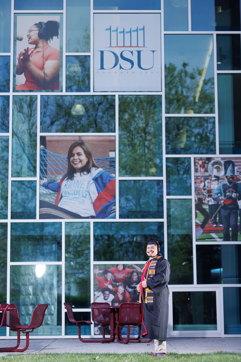 Modern university building facade with large windows displaying student life photographs.