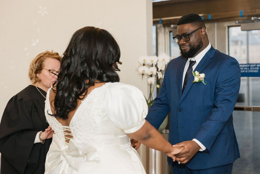 Intimate wedding ceremony with couple and officiant in front of white orchid decorations.