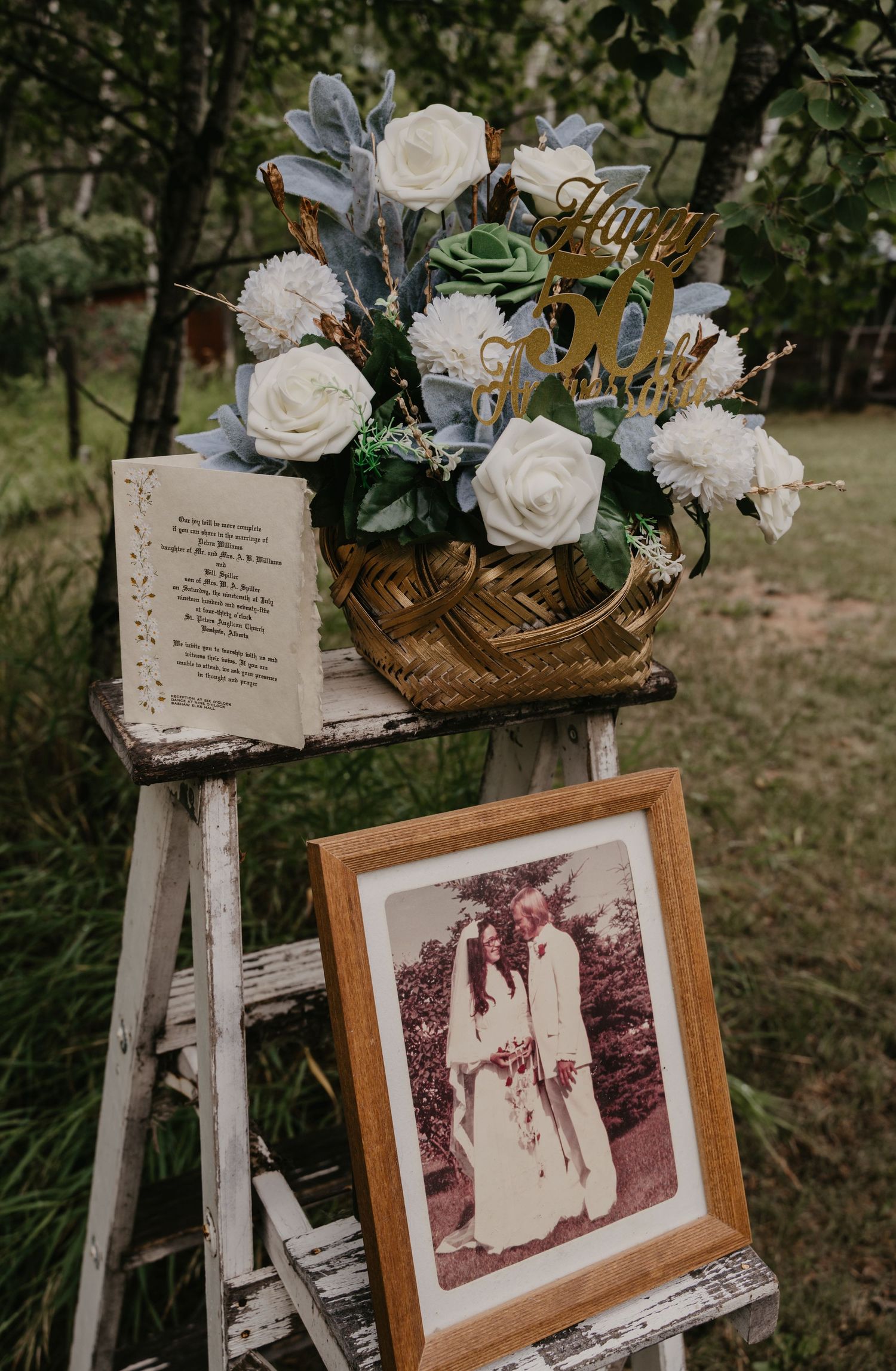 Wedding memorial display with vintage photographs and white roses in wooden frames.